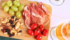 prosciutto, hrozny, cherry rajčata a ořechy na dřevěném prkénku