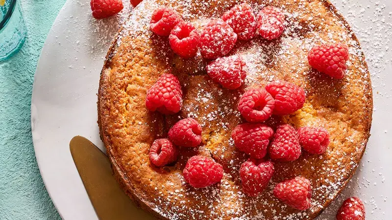 Malinový dort zdobený čerstvými malinami a moučkovým cukrem