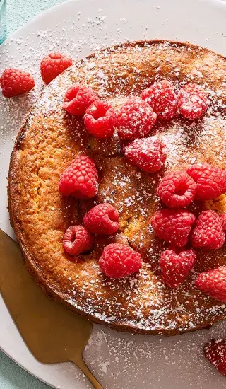 Malinový dort zdobený čerstvými malinami a moučkovým cukrem